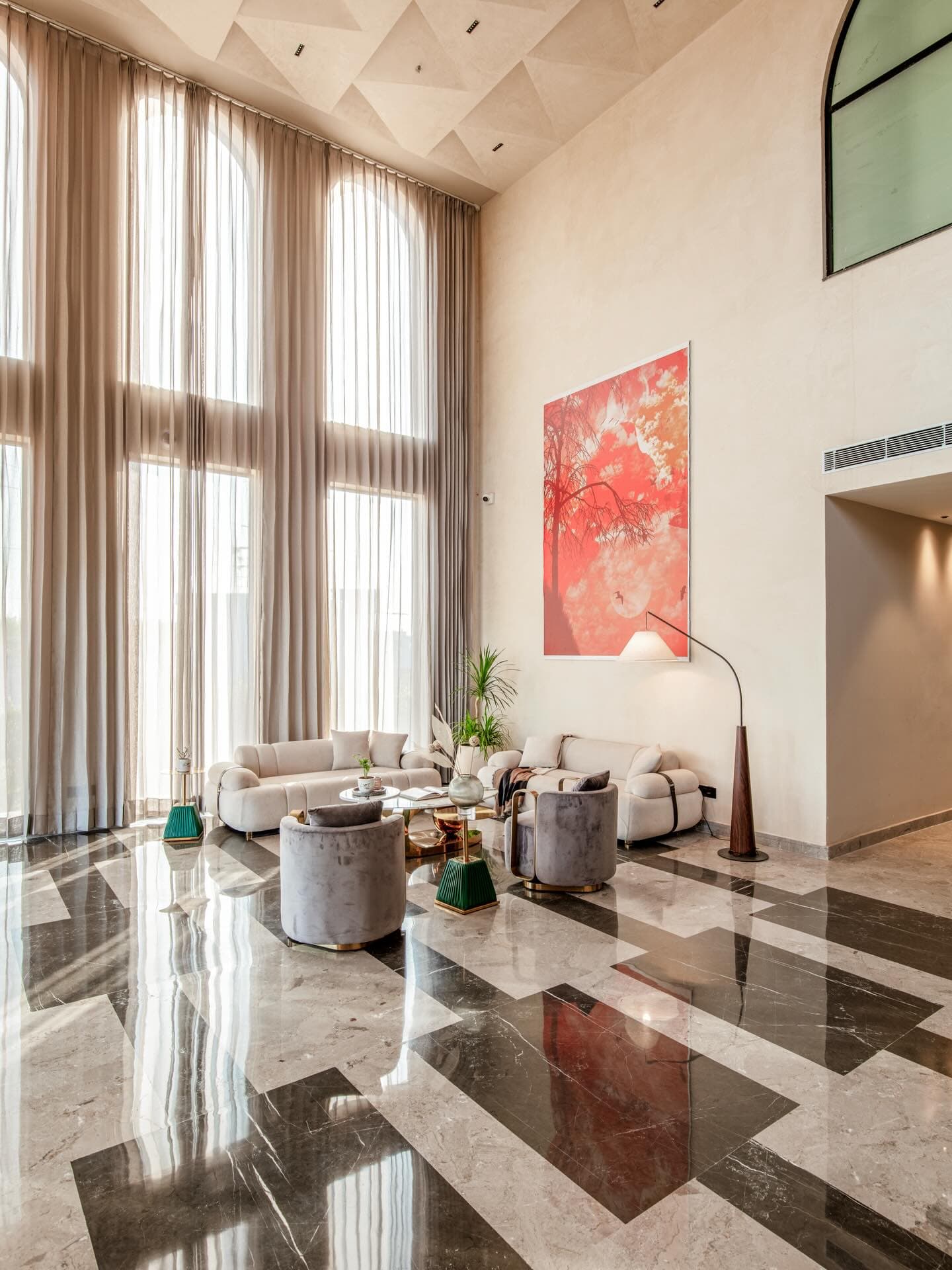 Double-height lounge at Hotel & Club Clarks Safari — arched sheer curtains, marble floor, warm plaster walls